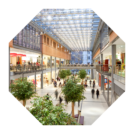 Image taken inside a shopping mall. There are lots of people walking around going to stores, buying things and consuming food and beverages. There are two floors with shops and boutiques. The ceiling is glass. The architecture is very modern and new and the general feel of the images is bright, clean, safe and positive.