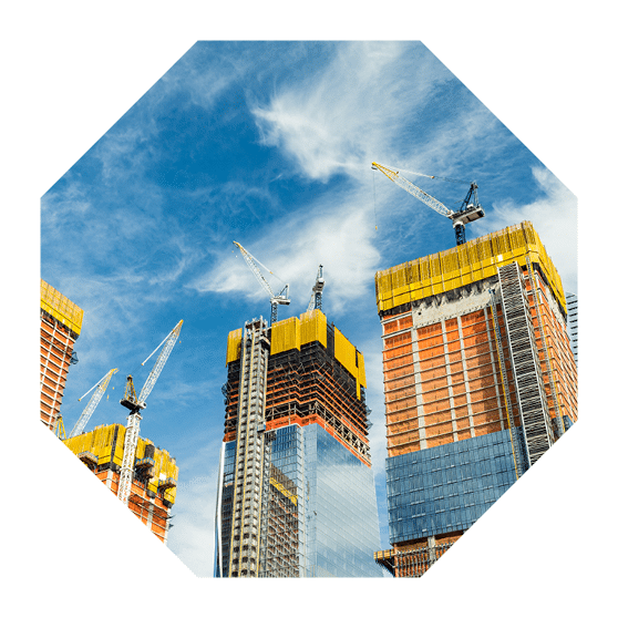 Skyscrapers construction site for modern buildings in New York. Cranes and scaffolding used to build tall structures, blue sky on background.